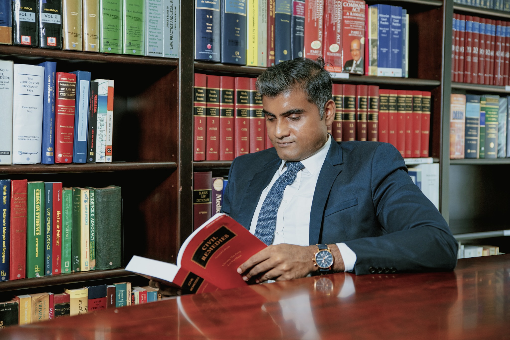 Vinobha Anthony Doss reading a copy of Civil Remedies in the firm's law library